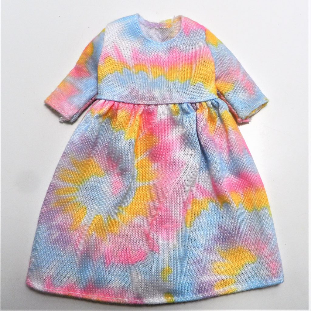 Her dress has soft pastel tie dye patterns and mid length sleeves